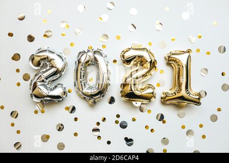 Gold und Silber Zahlen 2021 und festliche Konfetti auf weißem Hintergrund. Konzeptionelle Neujahr und Weihnachten Hintergrund. Stockfoto