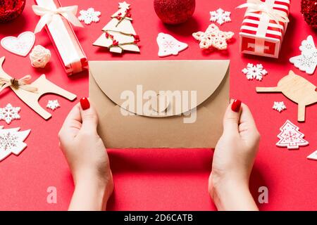 Blick von oben auf die Frau mit einem Umschlag auf rotem Hintergrund aus Urlaub Dekorationen. Weihnachten Konzept. Stockfoto