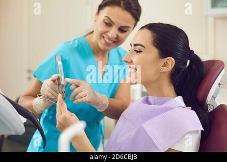 Glückliche Frau in Zahnarztstuhl Blick auf das Ergebnis Professionelle Zahnreinigung und Zahnaufhellung Stockfoto