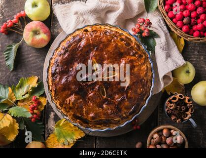 Hausgemachter Apfelkuchen umgeben von frischem Obst, Nüssen, Äpfeln Stockfoto