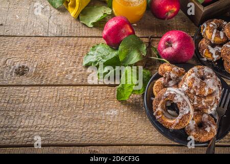 Herbst süße Dessert Rezept. Hausgemachte Apfelweindonuts. Gebackene Donuts mit Zucker, Zimtglasur und weißem Zuckerguss, auf Holzbackgroun Stockfoto