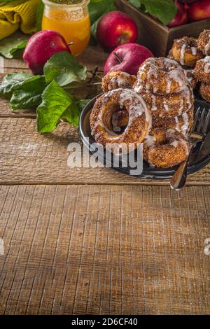 Herbst süße Dessert Rezept. Hausgemachte Apfelweindonuts. Gebackene Donuts mit Zucker, Zimtglasur und weißem Zuckerguss, auf Holzbackgroun Stockfoto