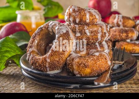 Herbst süße Dessert Rezept. Hausgemachte Apfelweindonuts. Gebackene Donuts mit Zucker, Zimtglasur und weißem Zuckerguss, auf Holzbackgroun Stockfoto