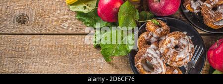 Herbst süße Dessert Rezept. Hausgemachte Apfelweindonuts. Gebackene Donuts mit Zucker, Zimtglasur und weißem Zuckerguss, auf Holzbackgroun Stockfoto