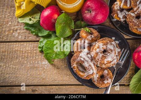 Herbst süße Dessert Rezept. Hausgemachte Apfelweindonuts. Gebackene Donuts mit Zucker, Zimtglasur und weißem Zuckerguss, auf Holzbackgroun Stockfoto