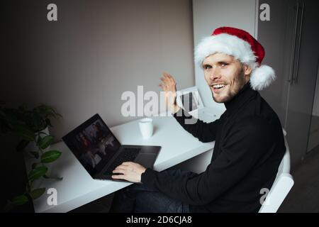 Geschäftsvideokonferenzen. Junger Mann mit Videoanruf über Computer im Heimbüro. Virtuelle Weihnachtsfeier. Remote-Online-Teambesprechung Stockfoto