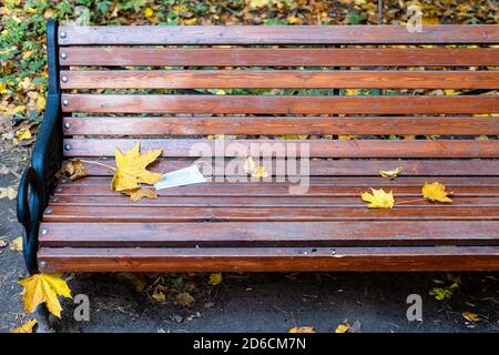 Geworfen medizinisches Gesicht fask auf hölzerne Bank im Stadtpark Am Herbsttag Stockfoto