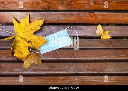 Draufsicht auf geworfen medizinischen Gesicht fask und gefallen Ahorn Die Blätter auf der Holzbank machen am Herbsttag die Nahaufnahme Stockfoto