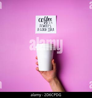 Papiertasse in menschlicher Hand und Karte mit Aufschrift Rosa Hintergrund Stockfoto