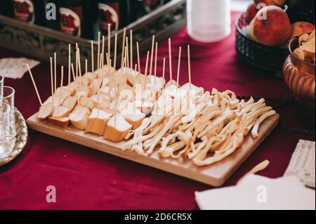 Seitenansicht eines Holzbretts mit Scheiben von verschiedenen Käsesorten auf Spieße. Catering. Stockfoto