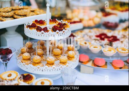 Hochzeitstorte mit bunten Cupcakes, Makronen, Kuchen, Gelee und Obst. Stockfoto