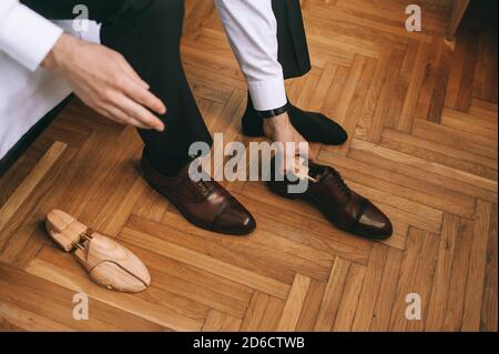 Nahaufnahme der Füße des Bräutigams oder Geschäftsmannes, der neue stilvolle Schuhe anzieht. Stockfoto