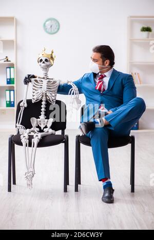 Geschäftsmann und Skelett im Büro in Pandemiekonzept Stockfoto