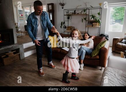 Vater und Tochter tanzen glücklich zusammen, während Mutter bequem sitzt Auf Wohnzimmer Sofa Stockfoto