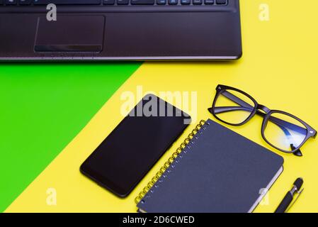 Büromaterial mit Stift, Papier Notebook, Smartphone, Laptop Brillen.Draufsicht.Working bunten Schreibtisch Stockfoto