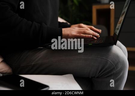 Junge kaukasische männliche Eingabe auf Laptop studieren für Online-Schule Sitzen im Schlafzimmer mit entspannter Atmosphäre Stockfoto