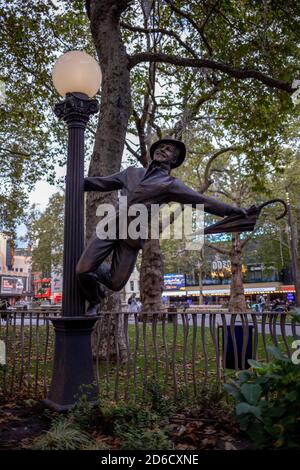 Eine Bronzestatue, die eine Szene aus dem Singen in der darstellt Regen mit Gene Kelly, der einen Regenschirm aus einem schwingenden trägt Lampenpfosten ist Teil einer Ausstellung Stockfoto