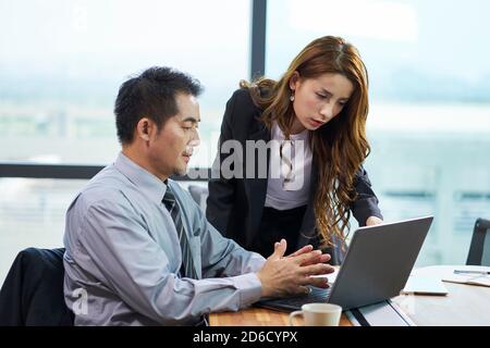 asiatische Geschäftsmann und Geschäftsfrau mit einer Diskussion im Büro mit Laptop-Computer Stockfoto