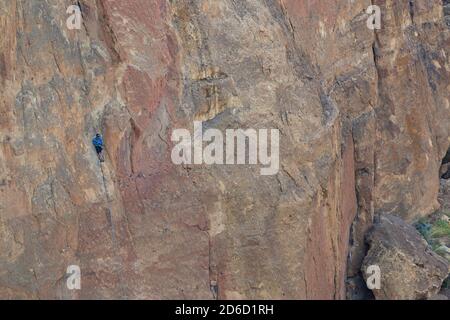 Nicht identifizierbarer Solo-Kletterer, der eine Pause auf den kleinsten Felsvorsprüngen auf der Seite des Smith Rock nördlich von Bend, Oregon, macht Stockfoto