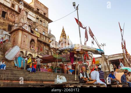 Varanasi, Uttar Pradesh, Indien : Menschen sitzen an den Ghats entlang des Ganges Flusses. Stockfoto