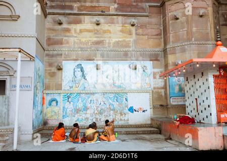 Varanasi, Uttar Pradesh, Indien: EINE Gruppe von saddhus sitzen durch einen kleinen Shiva-Schrein auf den Ghats. Stockfoto