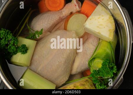 Ungekochte und rohe Hähnchen mit Wurzelgemüse in einem Topf Von oben Stockfoto