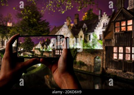 Touristen fotografieren historische Gebäude und Kanal in Brügge, Belgien. Ansicht des Fotos von der Bonifacius-Brücke und medialen Häusern Stockfoto