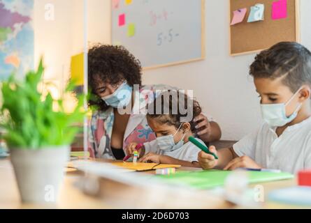 Lehrer mit Kindern tragen Gesichtsmaske in der Vorschule Klassenzimmer während corona Virus Pandemie - Gesundheits- und Bildungskonzept Stockfoto