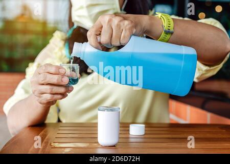 Frau tragen chirurgische Maske füllen Alkohol in Nano-Sprühnebel für die Handreinigung, um die Ausbreitung des Corona-Virus zu verhindern (Covid-19). Moderne Gesundheit t Stockfoto