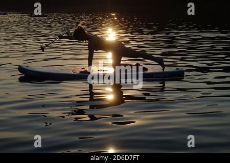 08.08.2020, Berlin, Deutschland - Frau am Abend bei SUP-Pilates am Schlachtensee. 00S200808D685CAROEX.JPG [MODEL RELEASE: JA, PROPERTY RELEAS Stockfoto