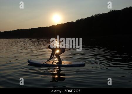 08.08.2020, Berlin, Deutschland - Frau am Abend bei SUP-Pilates am Schlachtensee. 00S200808D683CAROEX.JPG [MODEL RELEASE: JA, PROPERTY RE Stockfoto