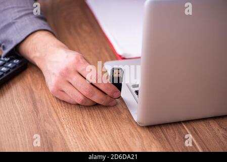 Männlicher Mitarbeiter, der Flash-Laufwerk in den Laptop einsteckt Stockfoto