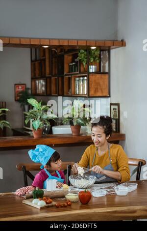 Mutter und Tochter haben Spaß zusammen kochen und lernen Machen Sie eine Pizza beim Backen in der Küche zu Hause Stockfoto