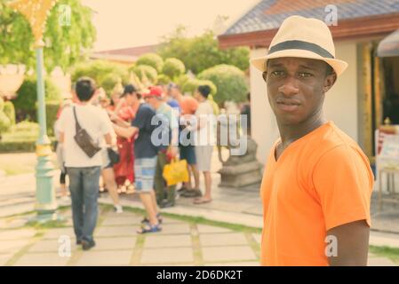 Junger afrikanischer Tourist Mann mit Gruppe von asiatischen Touristen nehmen Bilder mit thailändischen Frauen in traditioneller Kleidung Stockfoto