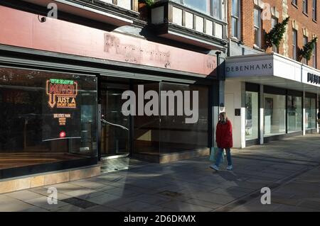 Ein Einzelkäufer passiert zwei kürzlich geschlossene große Namen auf der High Street - Pizza Hut und Debenhams - in Salisbury UK Okt 2020. Stockfoto