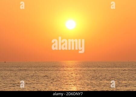 Ein schöner Sonnenuntergang am westerschelde Meer an einem heißen Sommerabend in zeeland, holland mit orangefarbenem Himmel und einem Sonnenstrahl über dem Wasser Stockfoto