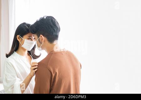 Ein Paar, das Masken trägt, kümmert sich um einander, in der Ära der Epidemie Stockfoto