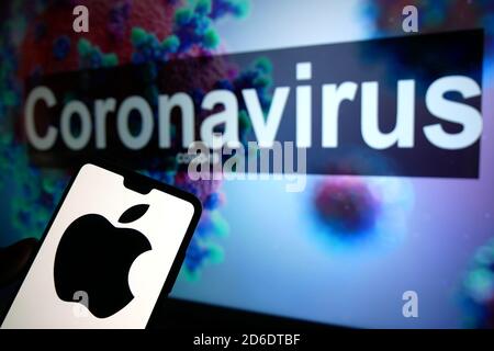 Das Apple-Logo auf einem Mobiltelefon mit einem illustrativen Modell des Coronavirus auf einem Monitor im Hintergrund. Stockfoto