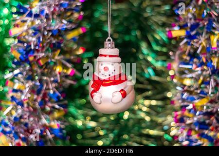 Vintage Glas Sowjetisches Neujahrsspielzeug (Schneemann) vor dem Hintergrund eines Weihnachtsbaums und farbenfroher heller Lametta. Stockfoto