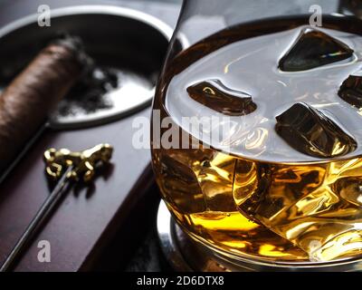 Whisky auf den Felsen und eine Zigarre in einem Aschenbecher Auf einer schwarzen Schieferfläche Stockfoto