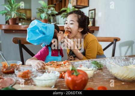 Mutter und Tochter sitzen in der Küche, essen Pizza und Spaß haben Stockfoto
