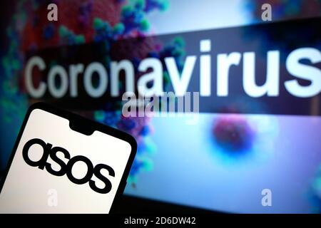 Das ASOS-Logo auf einem Mobiltelefon mit einem illustrativen Modell des Coronavirus, das auf einem Monitor im Hintergrund angezeigt wird. Stockfoto