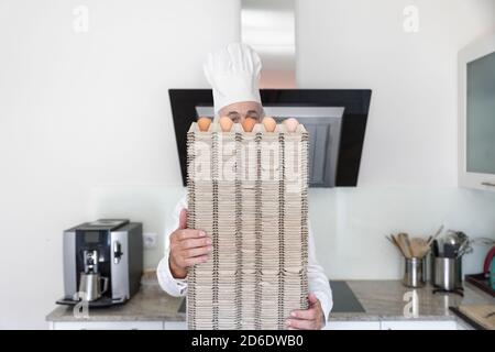 Koch kocht hinter einem Stapel Eierpaletten Stockfoto