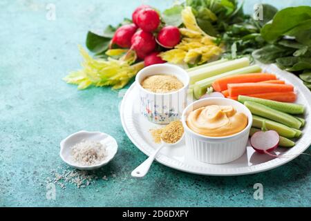 Paleo milchfreie Käsesauce, Hefeflocken und frisches Gemüse, selektiver Fokus Stockfoto