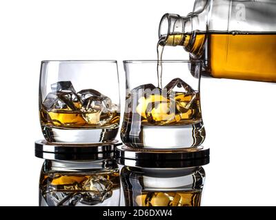 Whisky wird aus einer Flasche in ein Glas mit gegossen Eiswürfel auf weißem Hintergrund Stockfoto