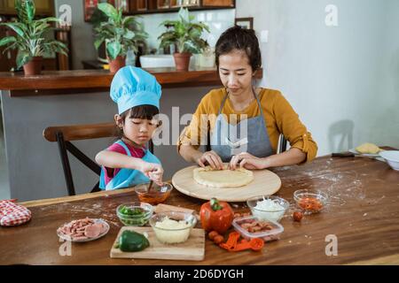Mutter und Tochter, die Pizza in der Küche vorbereiten Stockfoto