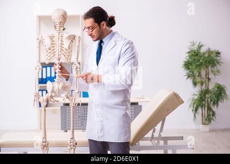 Junger männlicher Arzt mit dem Skelett Stockfoto