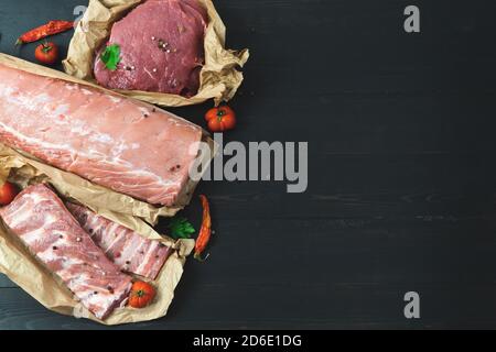 Verschiedene Fleischstücke, frisch auf dunklem Hintergrund. Speicherplatz kopieren. Stockfoto