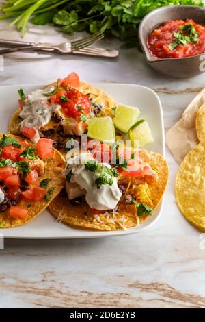 Mexikanisches Huhn tostada flaches Tacos mit Reis, schwarzen Bohnen, Salsa und saurer Sahne Stockfoto