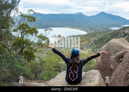 Junge Dame bewundert die Landschaft von Eaglehawk Neck mit offenen Armen in Tasmanien, Australien. Stockfoto